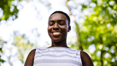 Woman smiling and closing her eyes with nature background